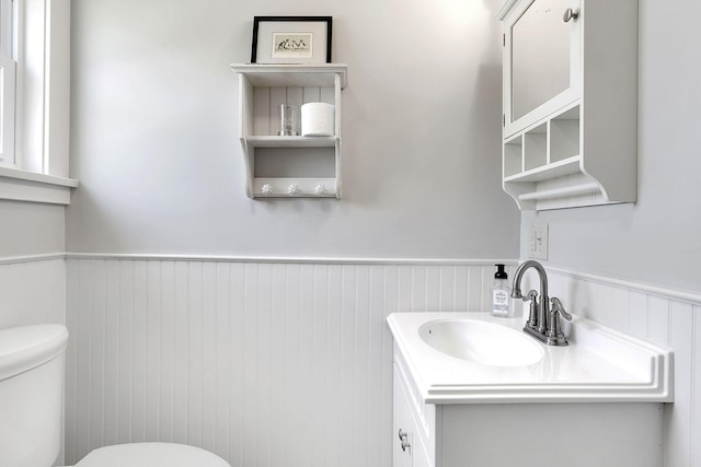 half bath featuring wainscoting, vanity, and toilet