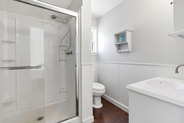 full bathroom with a wainscoted wall, a shower stall, toilet, and wood finished floors