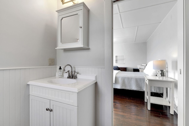 ensuite bathroom with wainscoting, ensuite bath, hardwood / wood-style floors, and vanity