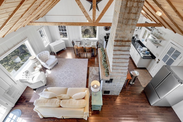 living area featuring lofted ceiling with beams, a wealth of natural light, visible vents, and wood finished floors