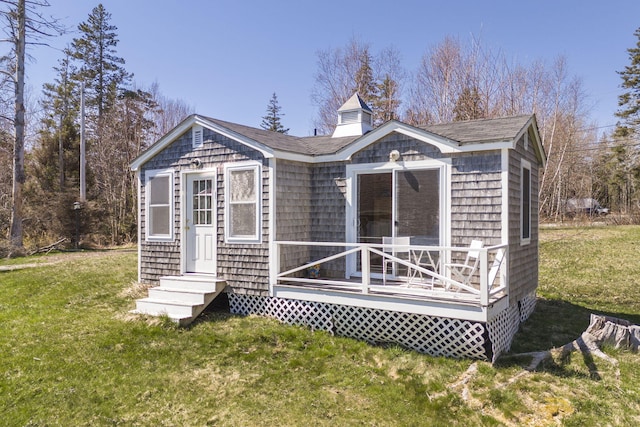 rear view of house featuring entry steps, a shingled roof, and a yard