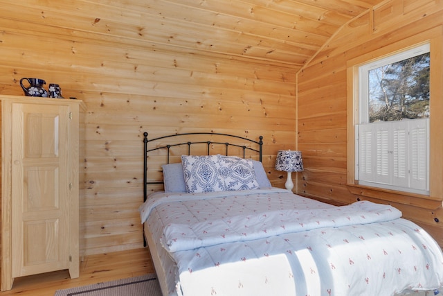 bedroom featuring lofted ceiling, wood walls, wooden ceiling, and wood finished floors