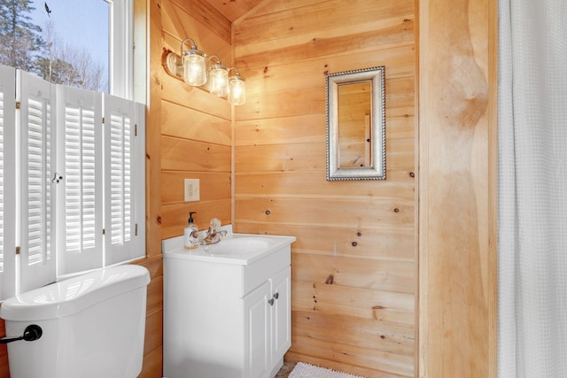 full bath featuring wood walls, vanity, and toilet