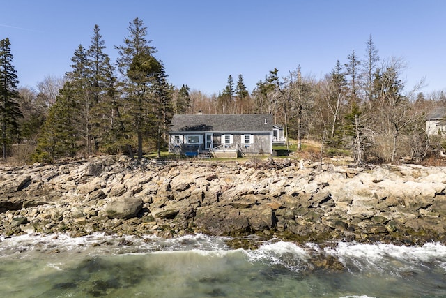 view of front of property with a wooden deck and a view of trees