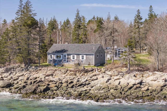 ranch-style home featuring a view of trees and a deck with water view