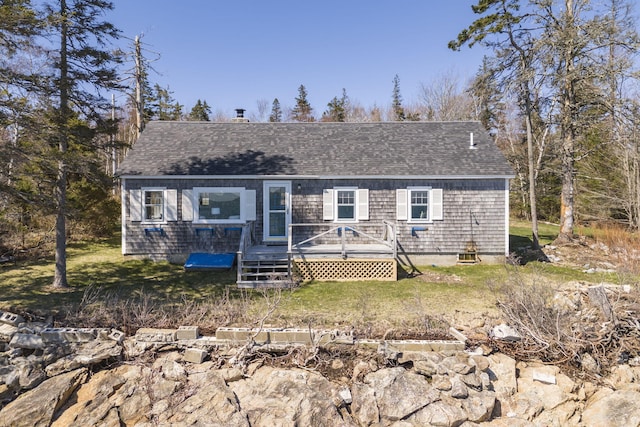 view of front of home featuring a wooden deck, a front yard, and roof with shingles