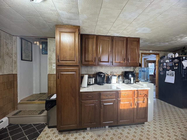 51 N Guilford Rd, Monson, ME 04464 - kitchen featuring freestanding refrigerator, light countertops, brown cabinetry, and wooden walls