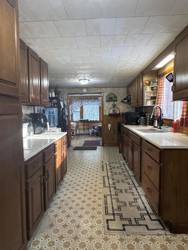 51 N Guilford Rd, Monson, ME 04464 - kitchen with light countertops, light floors, wood walls, black microwave, and a wainscoted wall