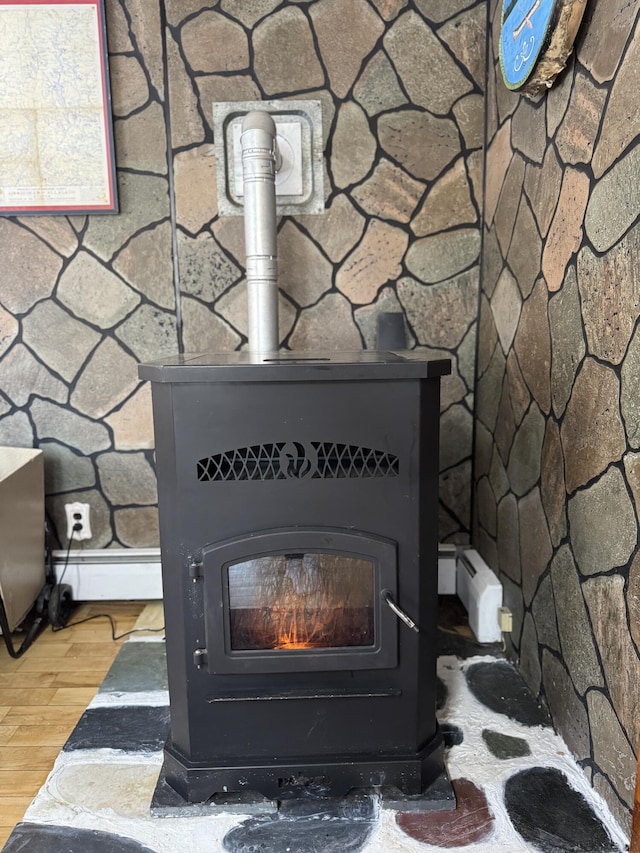 51 N Guilford Rd, Monson, ME 04464 - detailed view of a wood stove, a baseboard radiator, and wood finished floors