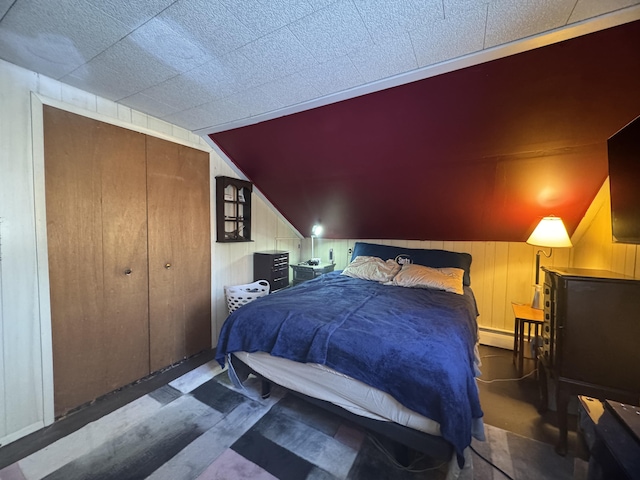 51 N Guilford Rd, Monson, ME 04464 - bedroom with wooden walls, a baseboard radiator, lofted ceiling, and a closet