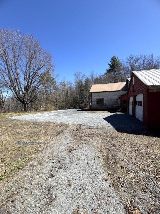 51 N Guilford Rd, Monson, ME 04464 - view of side of property featuring a metal roof, a garage, and driveway