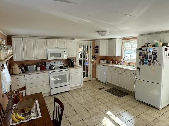 kitchen with white appliances, white cabinets, light countertops, and a sink