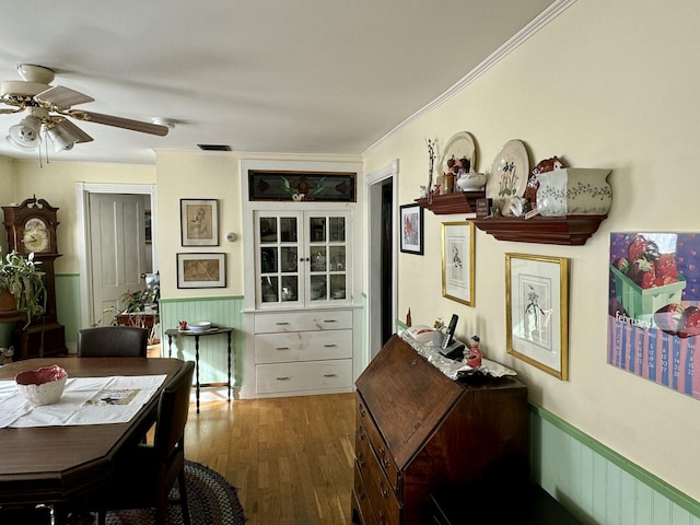 dining area featuring visible vents, wood finished floors, wainscoting, and crown molding