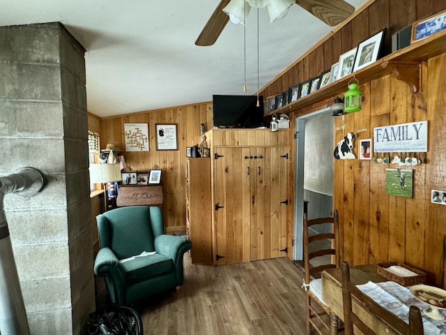 sitting room with ceiling fan, lofted ceiling, wood finished floors, and wood walls