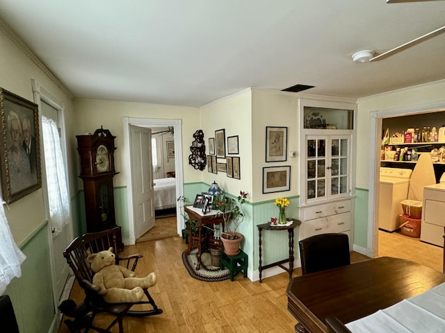 interior space featuring washer and dryer, light wood-type flooring, wainscoting, and crown molding