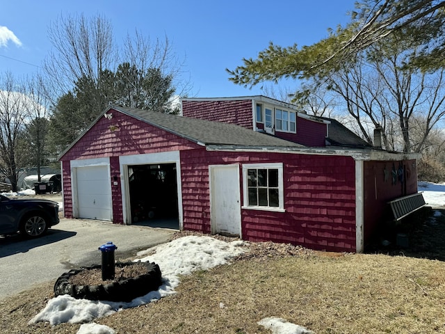 view of front of house with a garage, aphalt driveway, a chimney, and a shingled roof