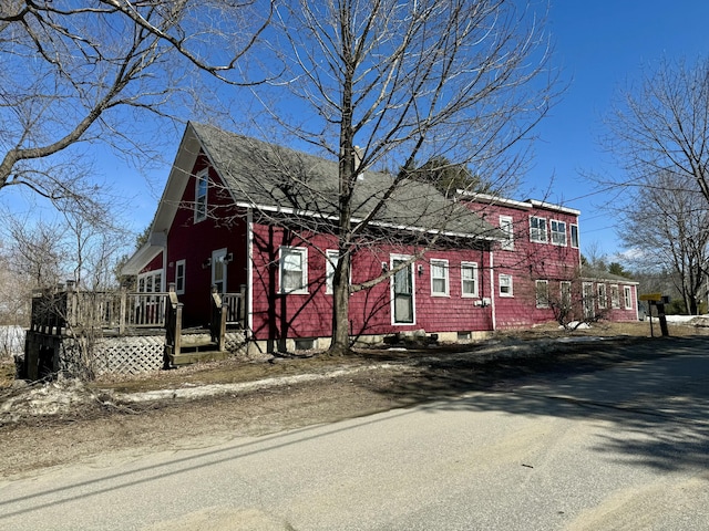 exterior space with a shingled roof and a deck