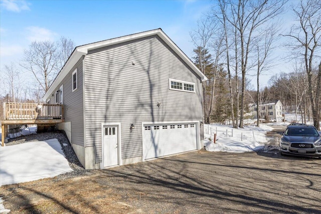 view of snowy exterior with a garage and a deck