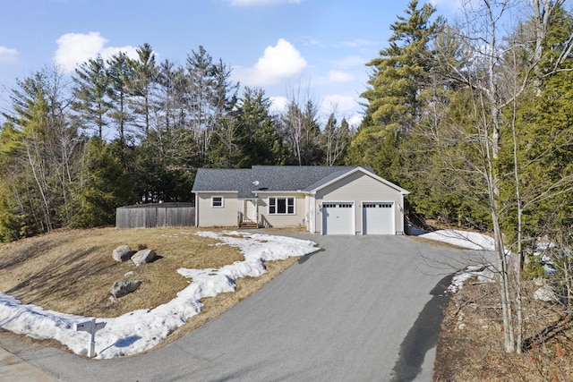 ranch-style home with aphalt driveway, a garage, and fence