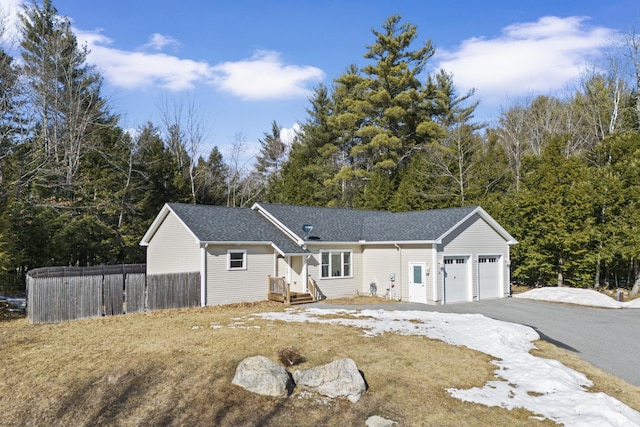 ranch-style house with aphalt driveway, fence, a garage, and a shingled roof