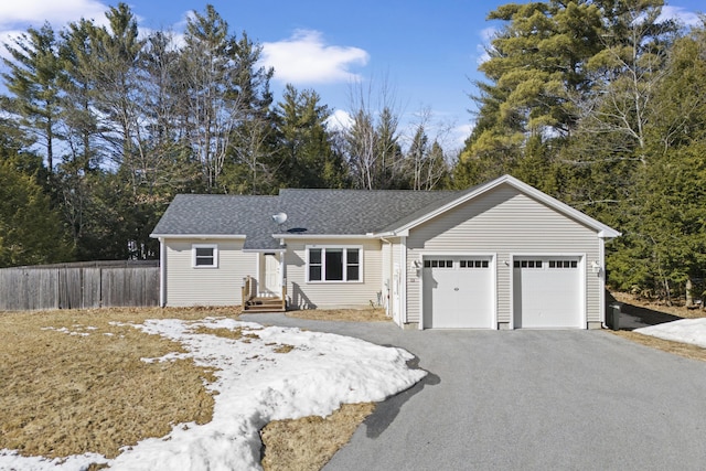 ranch-style home with aphalt driveway, fence, a garage, and a shingled roof