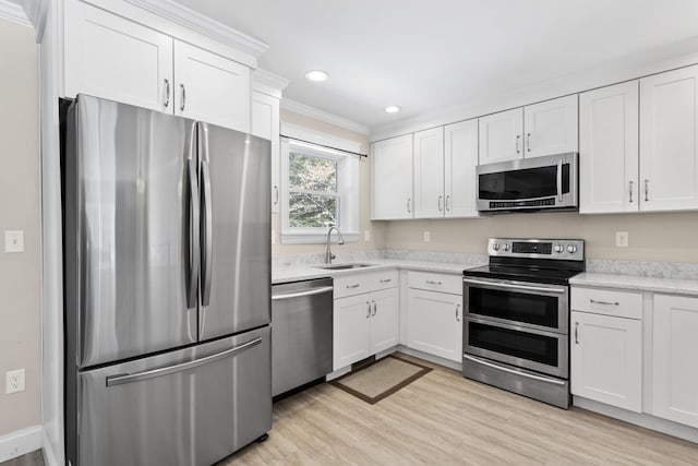 kitchen featuring a sink, recessed lighting, light wood-style floors, appliances with stainless steel finishes, and white cabinets