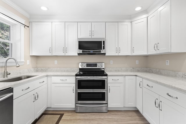 kitchen with a sink, light wood-type flooring, appliances with stainless steel finishes, and white cabinets