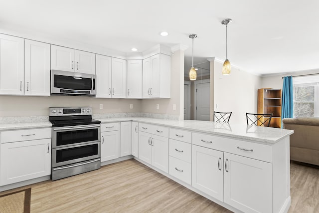 kitchen featuring crown molding, open floor plan, light wood-style flooring, a peninsula, and stainless steel appliances