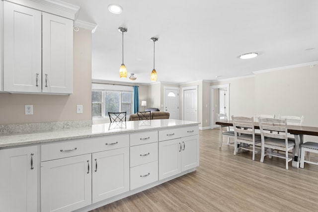 kitchen featuring white cabinetry, a peninsula, light wood-type flooring, and ornamental molding