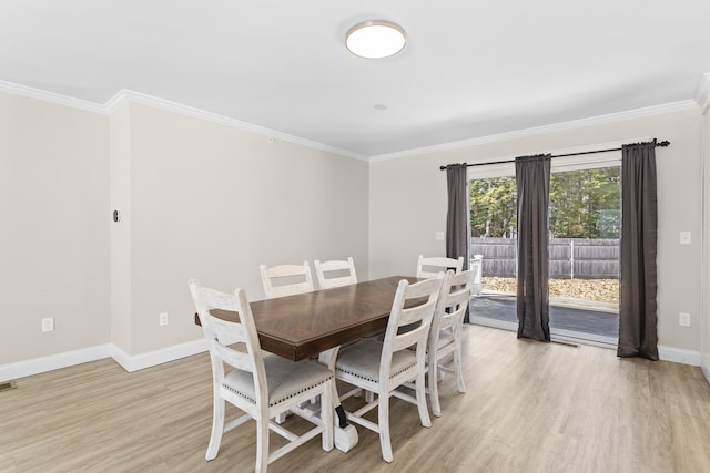 dining room featuring baseboards, light wood-style flooring, and ornamental molding