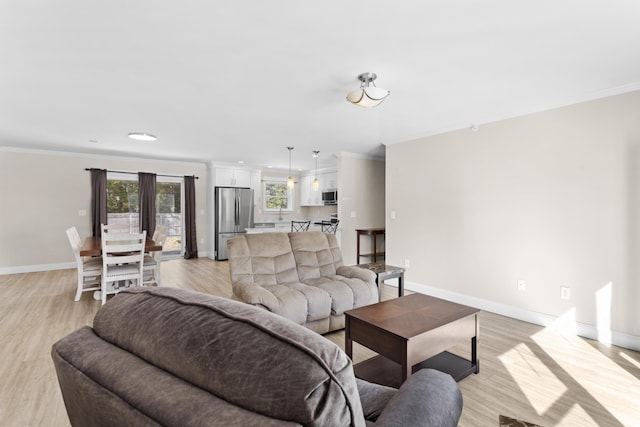 living room featuring crown molding, plenty of natural light, and light wood-style floors