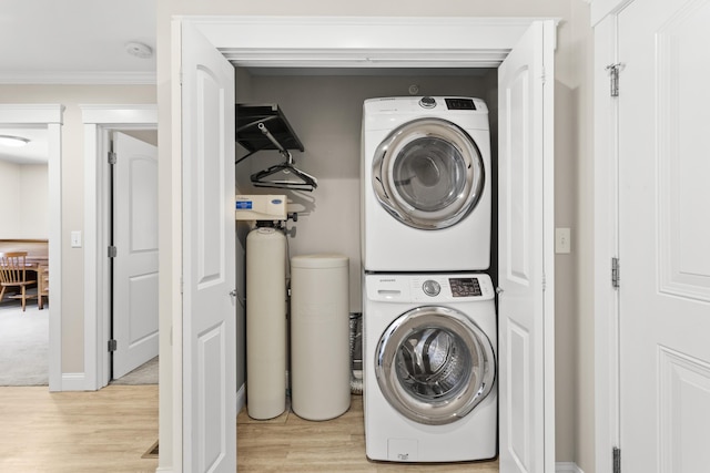 washroom with laundry area, light wood-type flooring, crown molding, and stacked washer and dryer