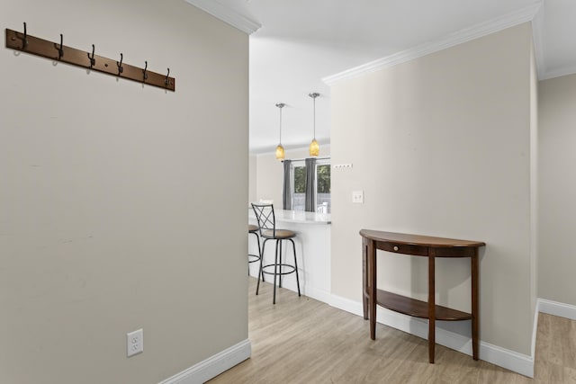 hallway with wood finished floors, baseboards, and ornamental molding