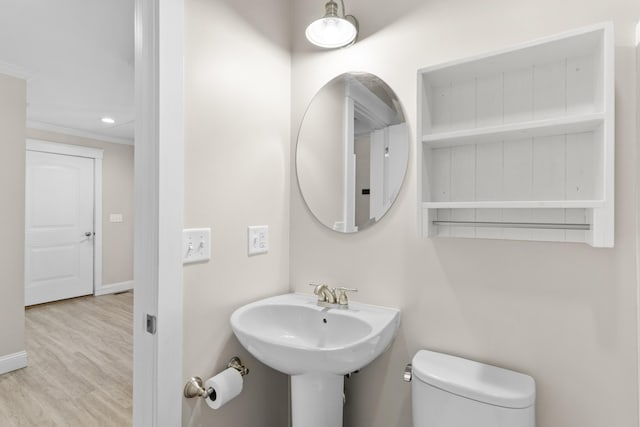 bathroom with crown molding, toilet, wood finished floors, and baseboards