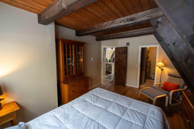 bedroom featuring wood ceiling, lofted ceiling with beams, baseboards, and wood finished floors