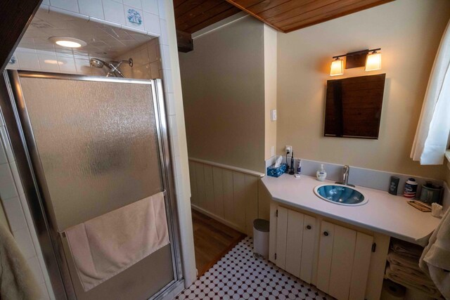 bathroom with a stall shower, wainscoting, and vanity