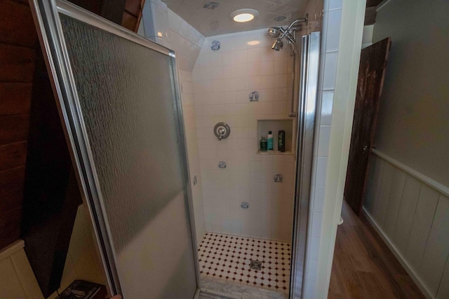 full bath featuring a shower stall, wood finished floors, and wainscoting