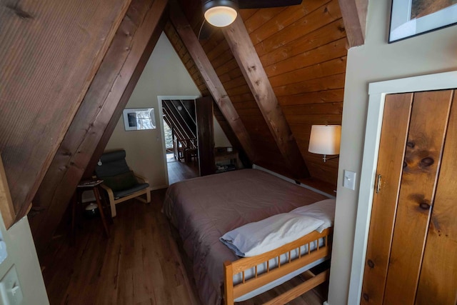 bedroom with lofted ceiling with beams and wood finished floors