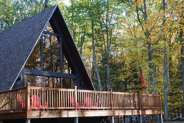 back of house with a shingled roof and a deck