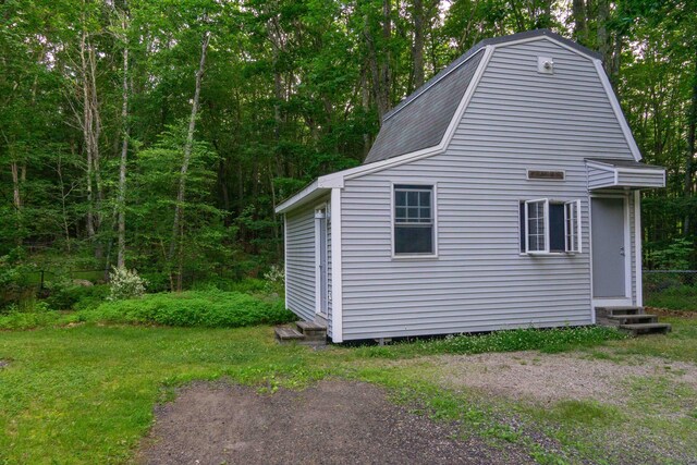 view of side of home with entry steps, roof with shingles, a yard, and a gambrel roof