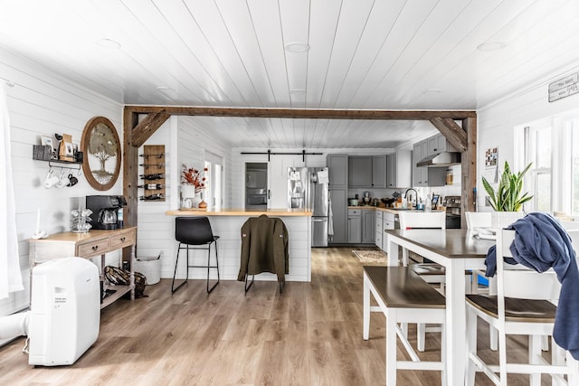 dining area featuring a barn door, wood ceiling, and light wood-style floors