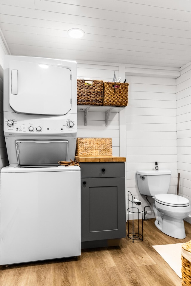 laundry area with laundry area, light wood-style floors, and stacked washer / drying machine