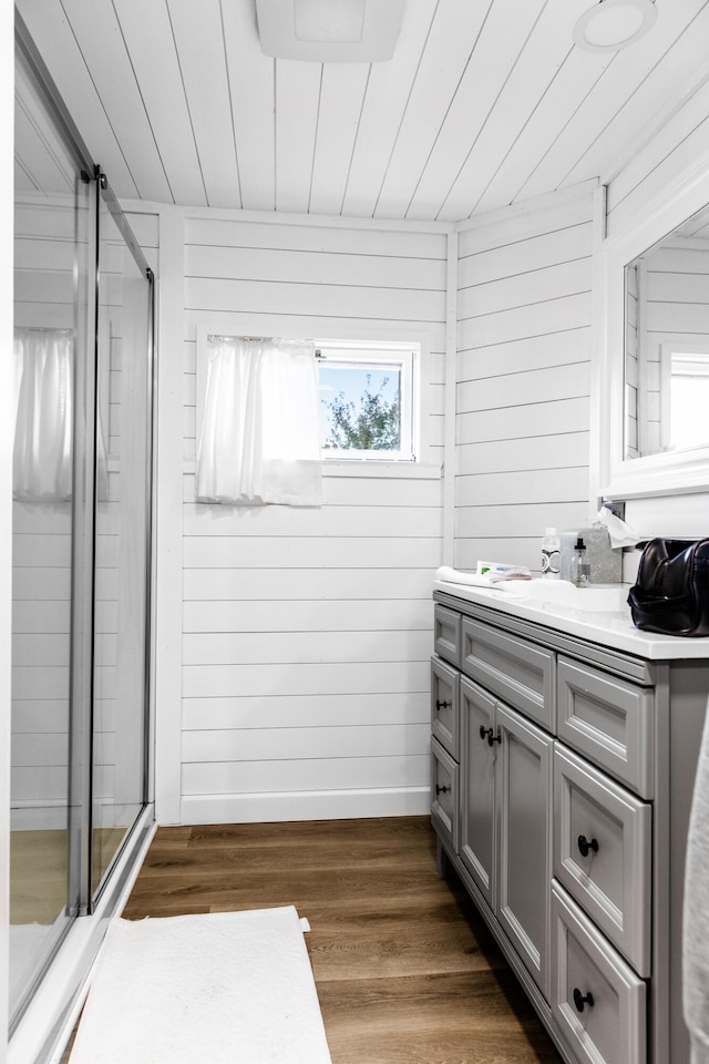 full bath featuring wooden walls, wooden ceiling, wood finished floors, vanity, and a shower stall