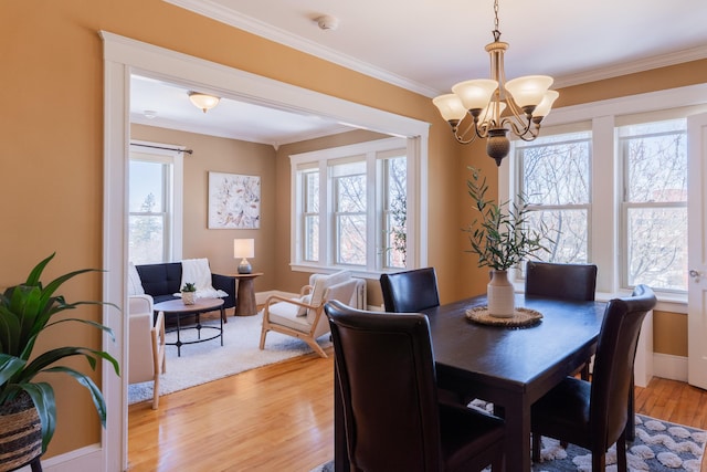 dining space featuring a chandelier, crown molding, light wood-style flooring, and baseboards