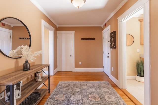 entryway with ornamental molding, light wood-style floors, and baseboards