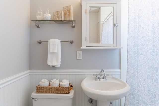 bathroom with a wainscoted wall, a sink, and toilet