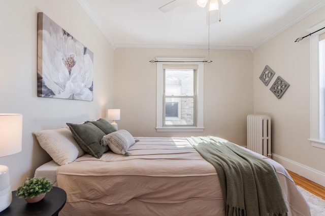 bedroom featuring ceiling fan, wood finished floors, baseboards, radiator heating unit, and crown molding