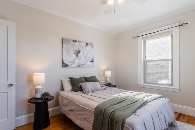 bedroom with ceiling fan, crown molding, baseboards, and wood finished floors