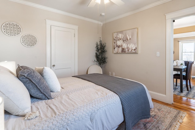 bedroom featuring a ceiling fan, crown molding, baseboards, and wood finished floors