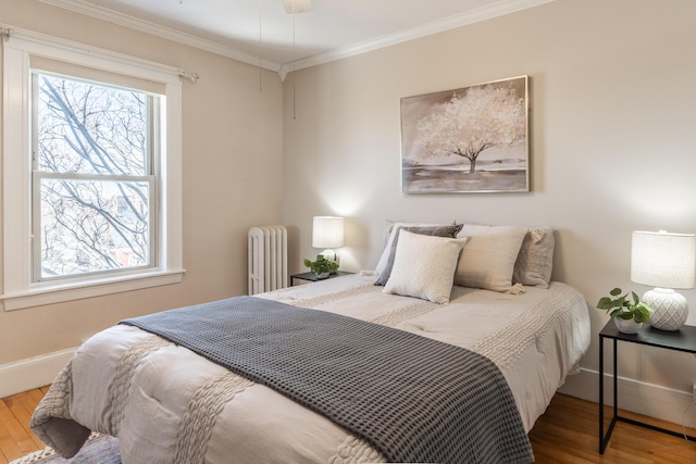 bedroom featuring radiator, baseboards, crown molding, and wood finished floors